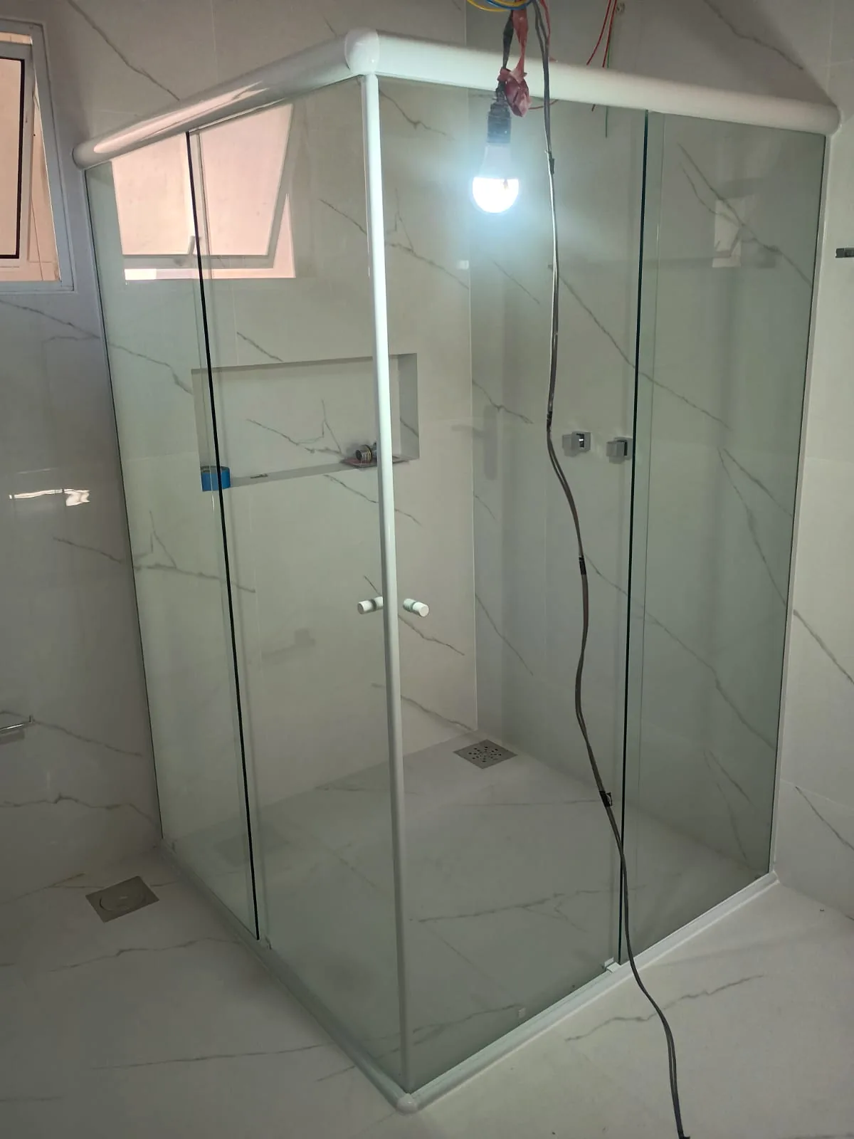 Box de vidro para banheiro com perfil branco, fotografado em ângulo
